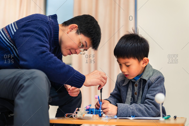 Father and child concentrate their attention on  assembling robot carefully