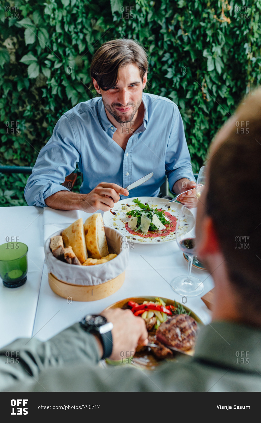 Two male friends having conversation while eating dinner at a restaurant