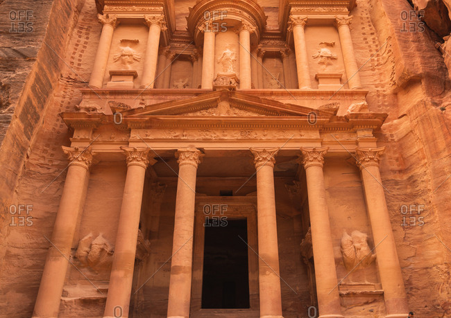 Petra, Jordan February 20, 2019: Facade of beautiful temple with columns carved in solid sandstone cliff stock photo - OFFSET