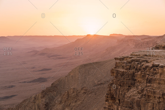 Panorama of empty dry desert with rough rocky cliffs on background of sunset sky, Israel