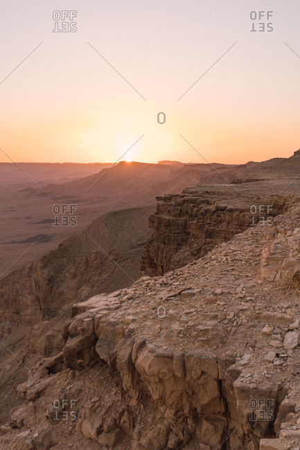 View of rocky cliffs in dry vast Negev desert with sunset sky on background, Israel