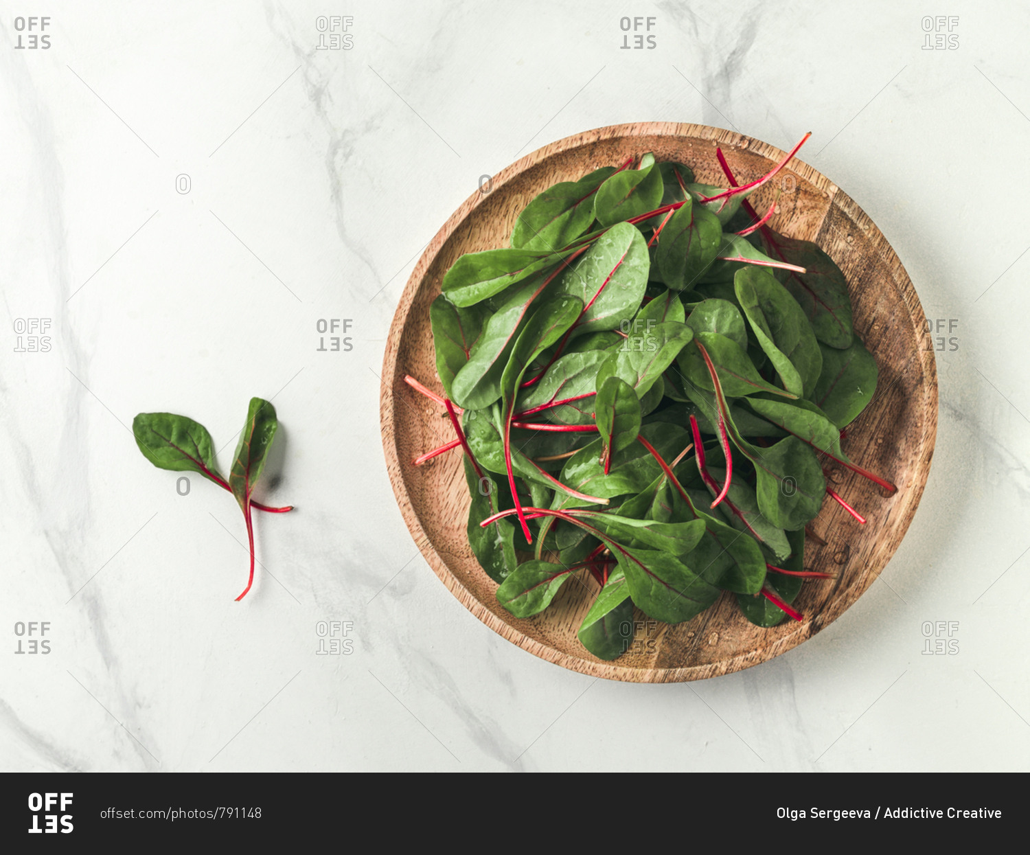 Fresh salad of green chard leaves or mangold on white marble background. Flat lay or top view fresh baby beet leaves on wooden plate. Copy space for text.