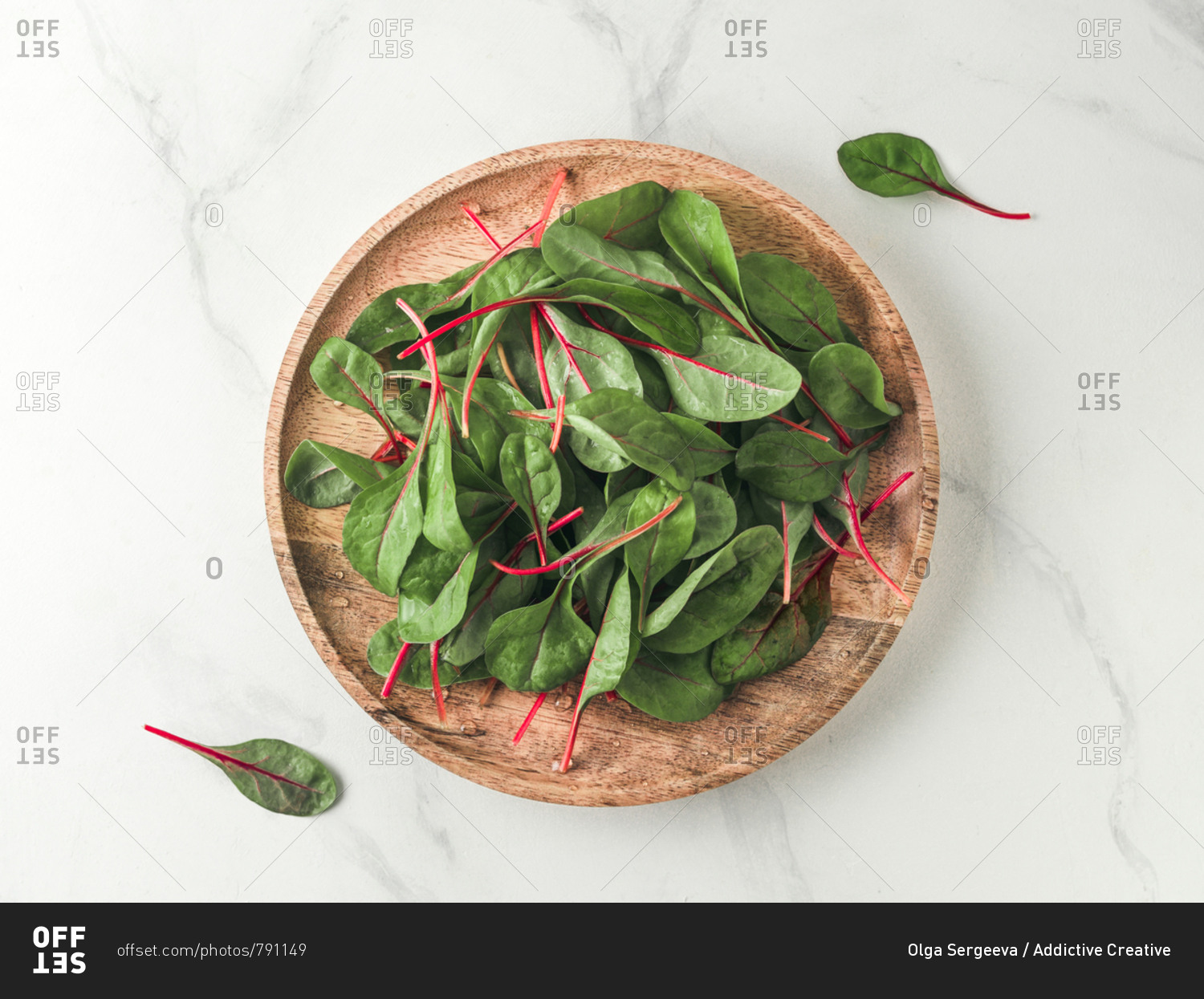 Fresh salad of green chard leaves or mangold on white marble background. Flat lay or top view fresh baby beet leaves on wooden plate. Copy space for text.