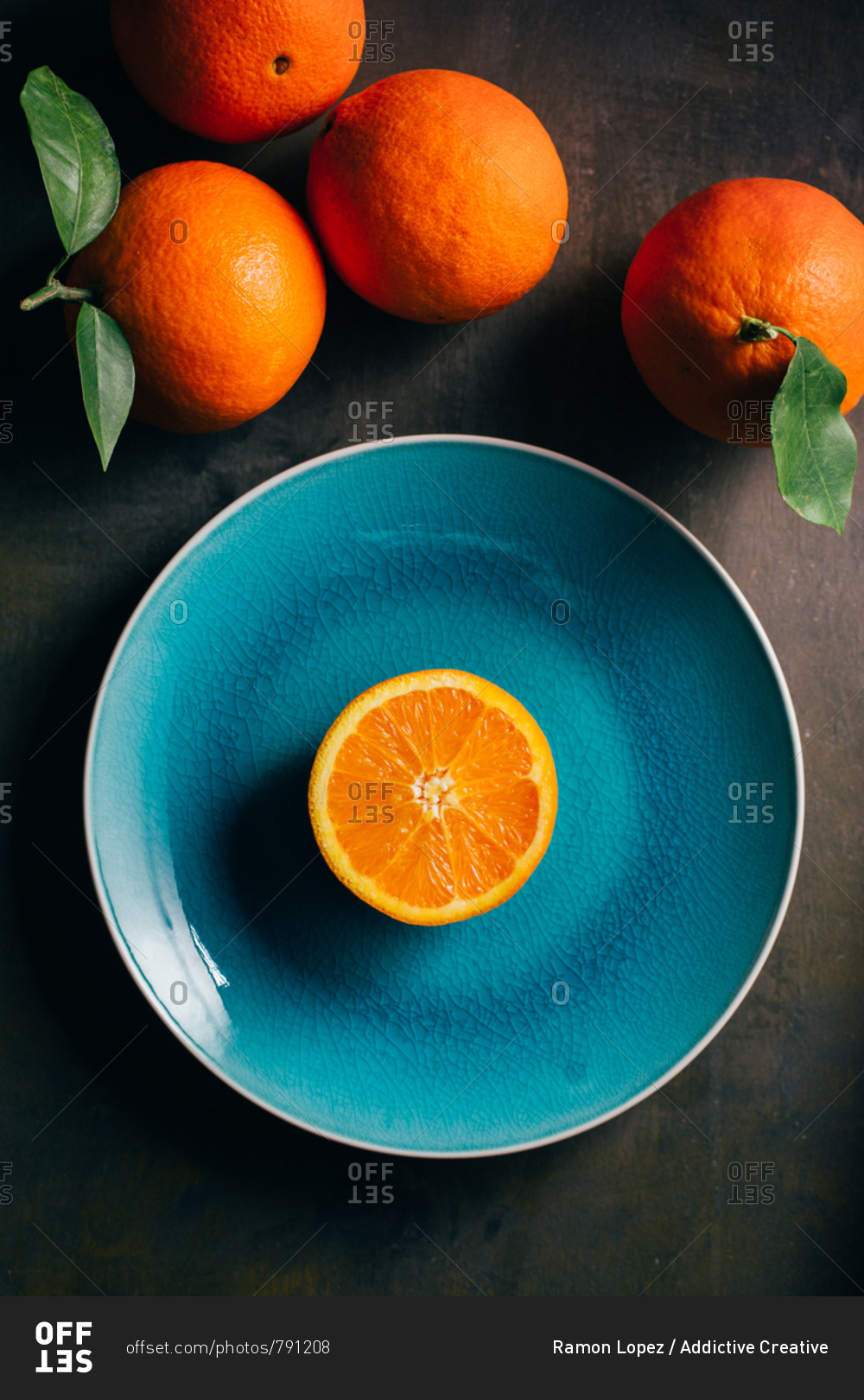 Fresh orange in a teal plate on dark background