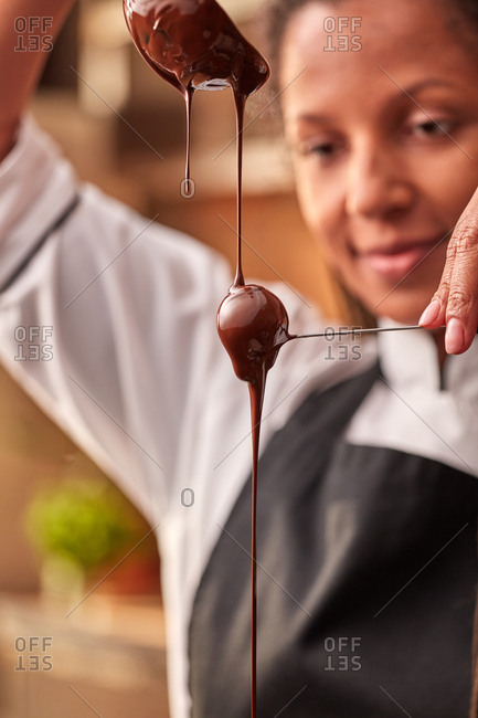 Chef confectioner afro female cook in process of preparing organic delicious handmade chocolate candy at the kitchen. Step by step process making of chocolate candy.