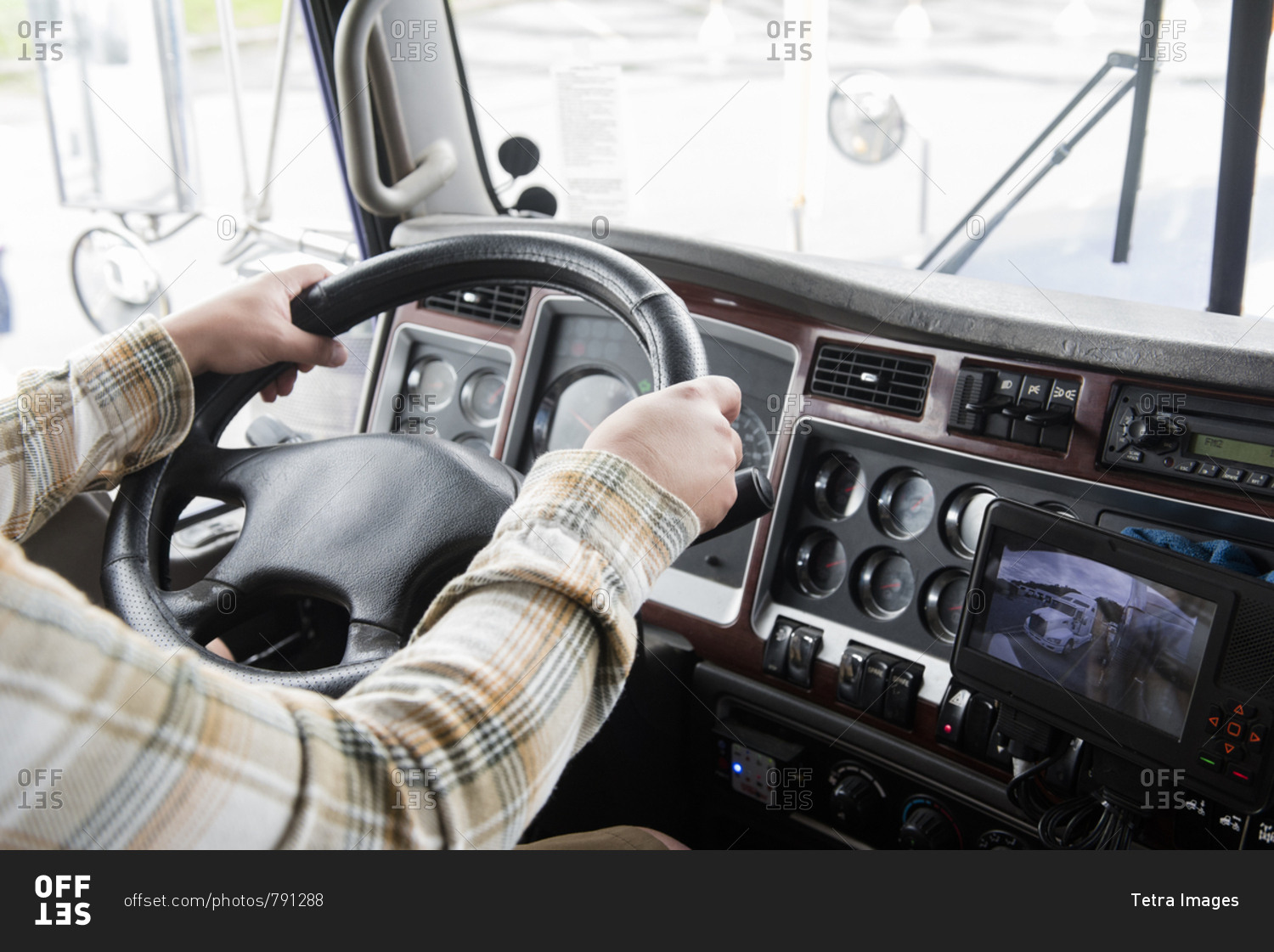 Hands of truck driver operating semi-truck