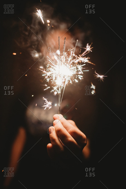 Hand holding several sparklers at nighttime