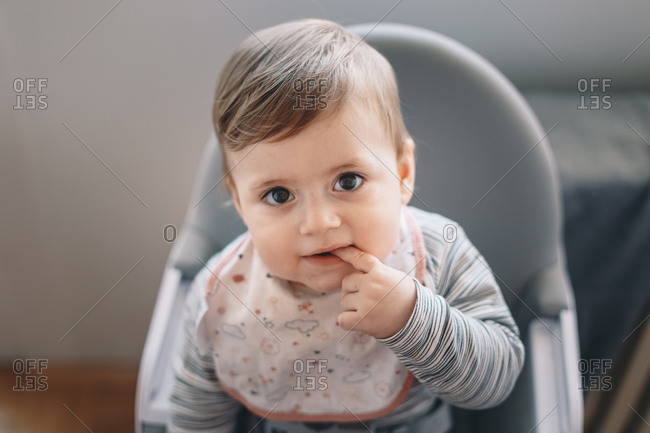 Adorable 10 month old baby boy sitting in a feeding chair