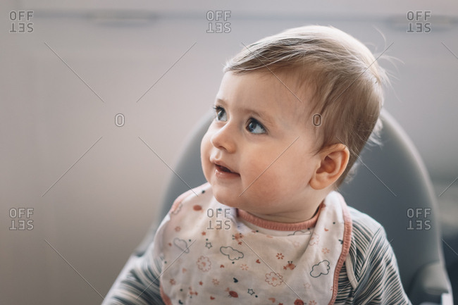 Adorable 10 month old baby boy sitting in a feeding chair