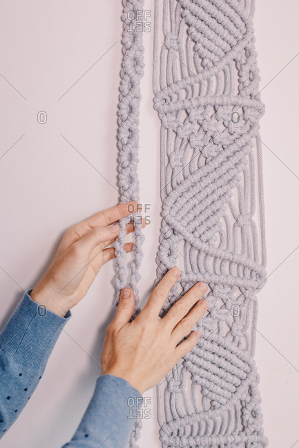 Woman's hands displaying a wall hanging macrame.