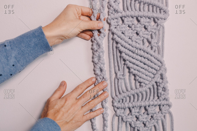 Female hands arranging a wall hanging macrame.