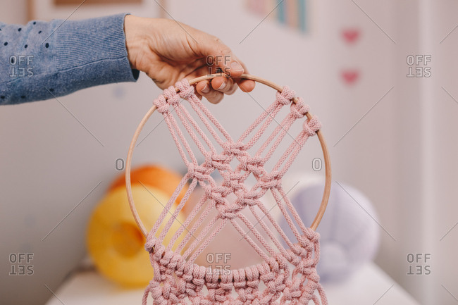 Woman's hands displaying an authentic homemade pink macrame.