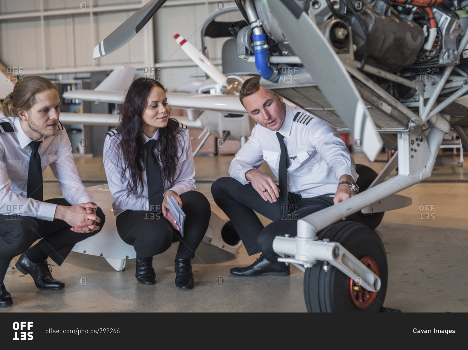 Engineer showing airplane wheel to trainees in hangar