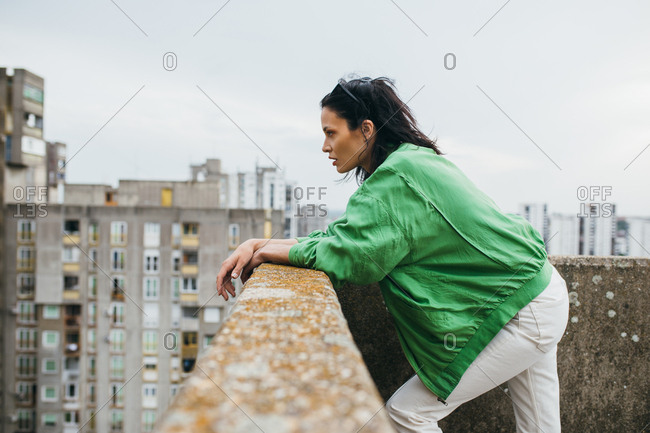 Beautiful attractive woman fashion model  posing on a rooftop wearing green jacket.