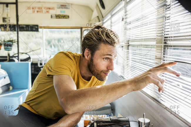 Man in an old bus peeking through sunblind