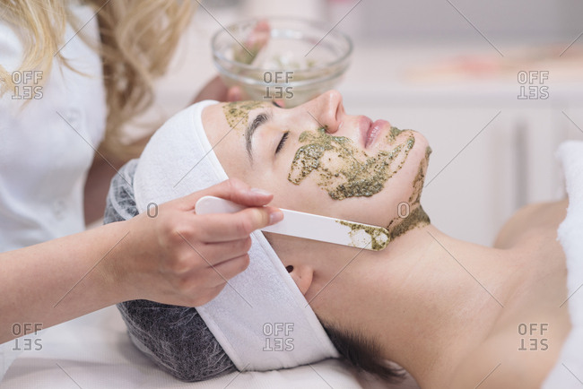 Cosmetician putting face peeling mask on a client