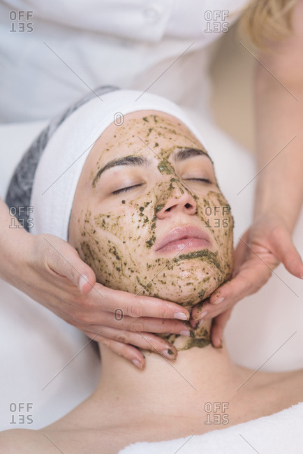 Cosmetologist putting face peeling mask on client