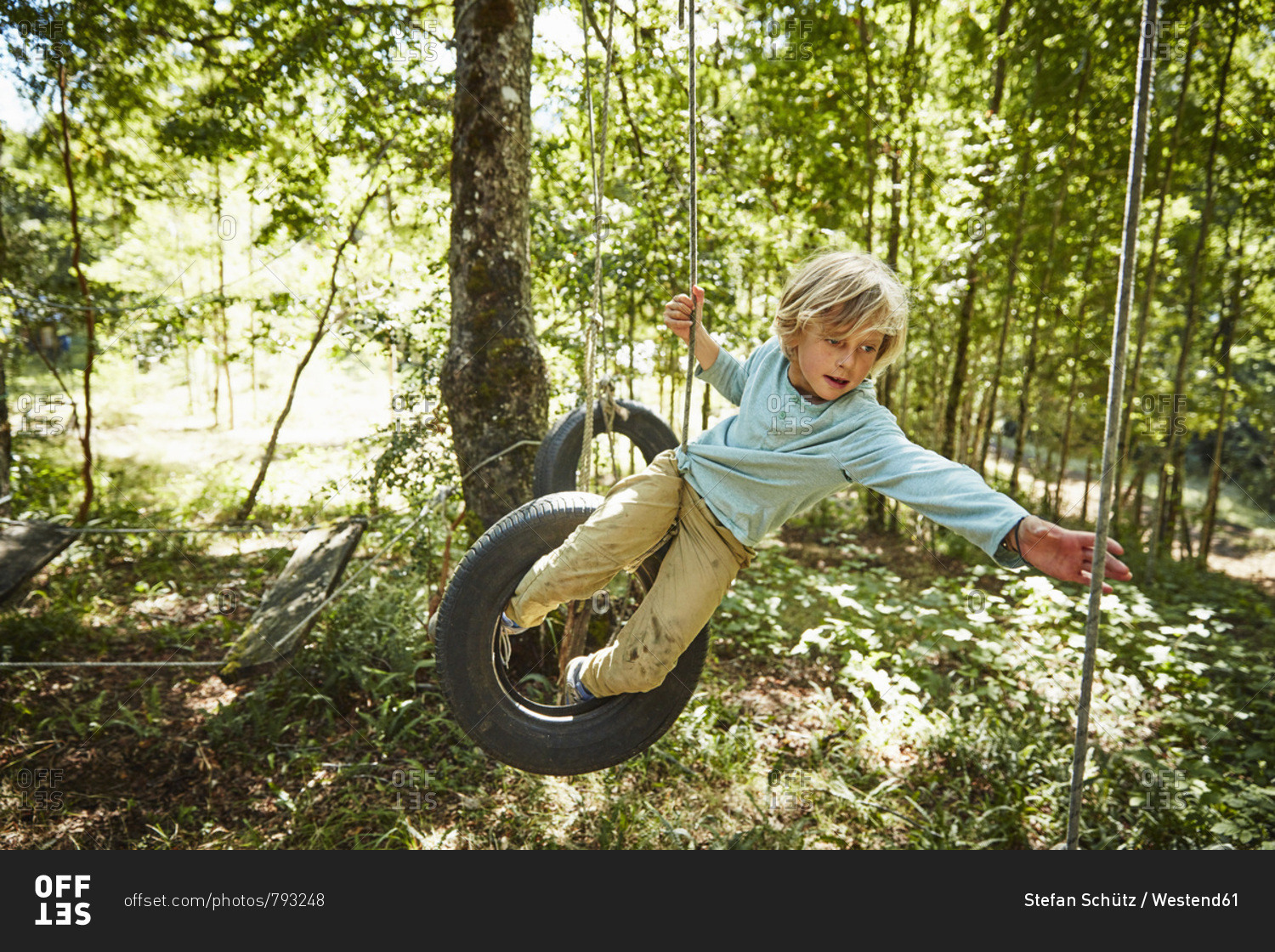 Boy balancing on tires at an adventure park in forest