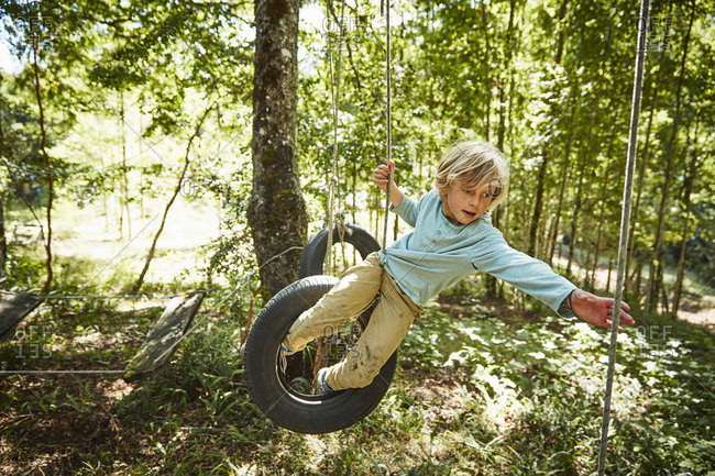 Boy balancing on tires at an adventure park in forest