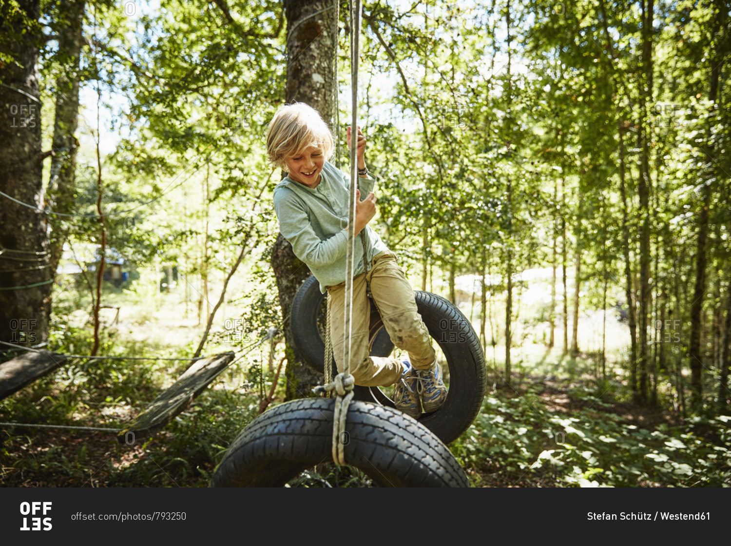 Happy boy balancing on tires at an adventure park in forest