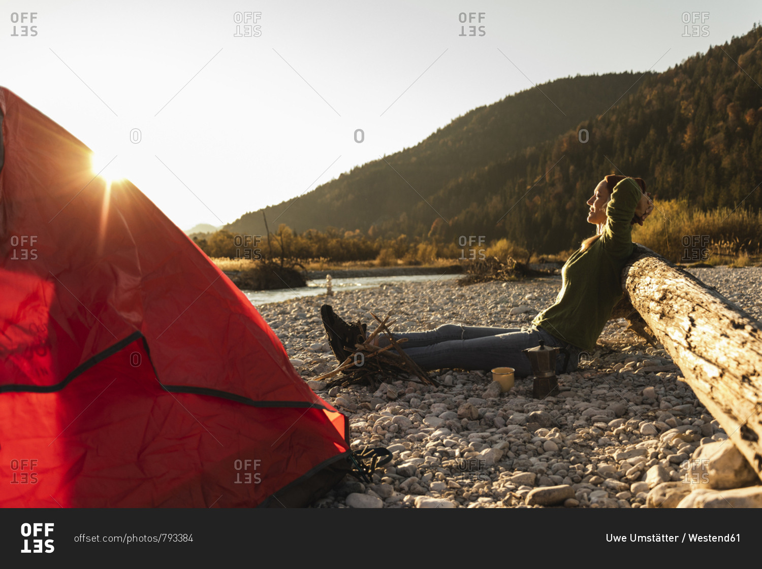 Mature woman camping at riverside in the evening light