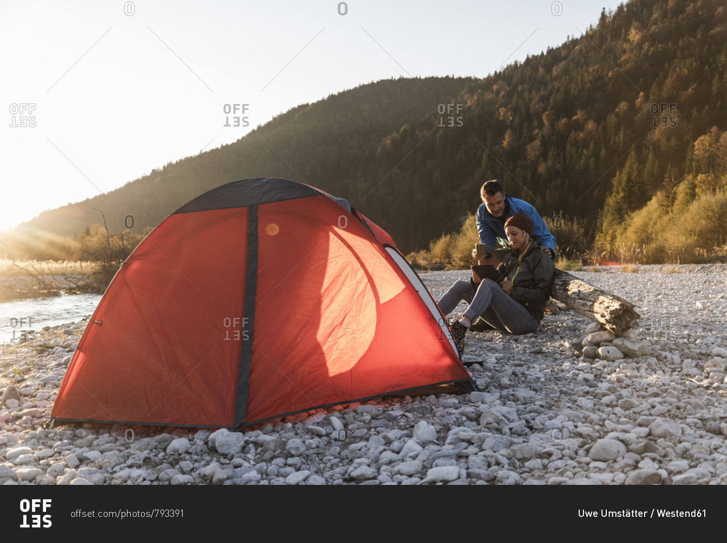 Mature couple camping at riverside in the evening light