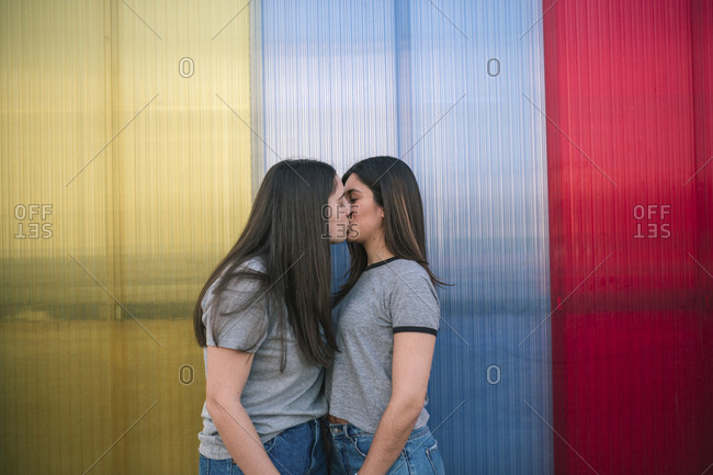 Caucasian lesbian couple who are kissing with a colorful background