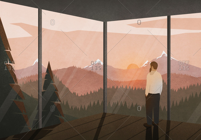 Man enjoying tranquil view of sunset behind mountains from glass house