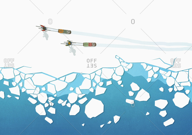 View from above people cross country skiing, pulling sleds over frozen ocean