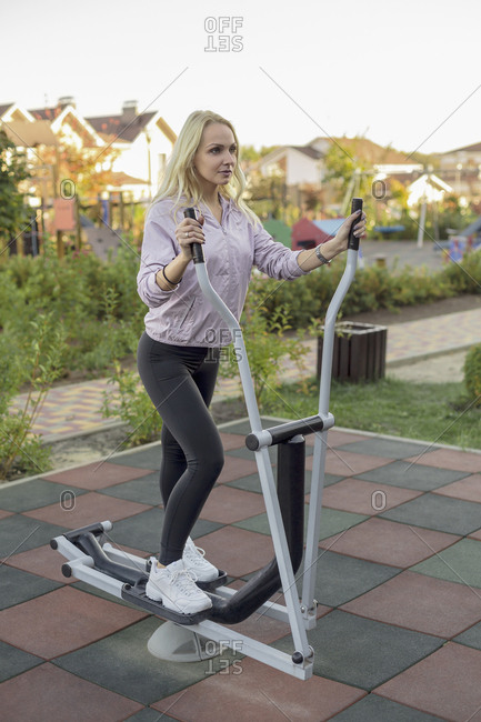 Fit woman using elliptical machine on patio