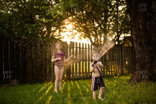 Two kids playing with hose in the summertime