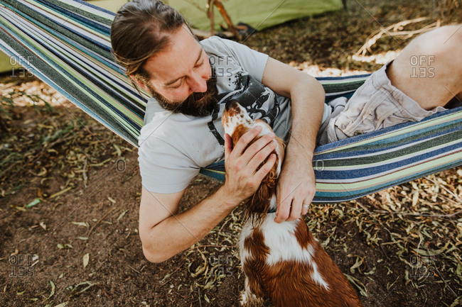 Man resting in hammock petting dog