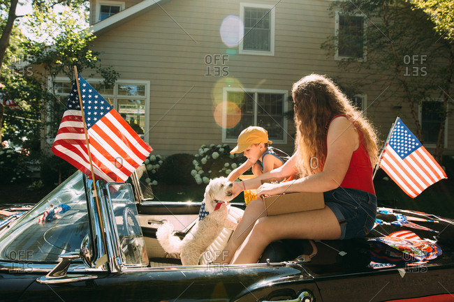 Boy sitting with woman and dog in a convertible on fourth of July