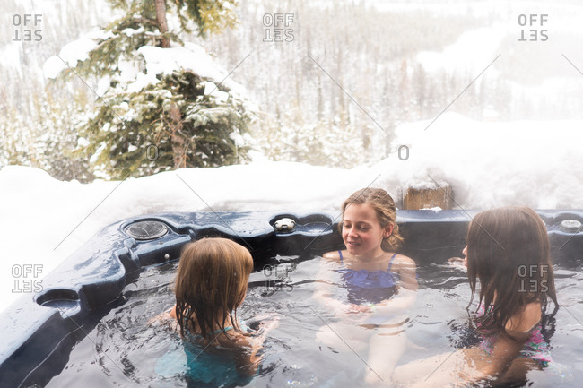 Three kids in a hot tub outside during winter