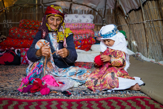 Old woman and her granddaughter in tent knitting