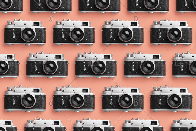 Photo cameras organized in a row over coral color background