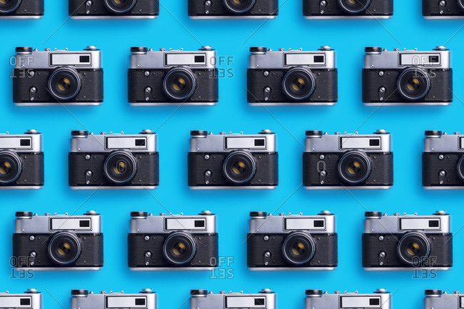 Photo cameras organized in a row over blue background
