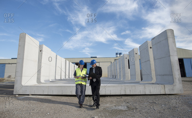 Businessman talking with female worker on industrial site in front of concrete blocks