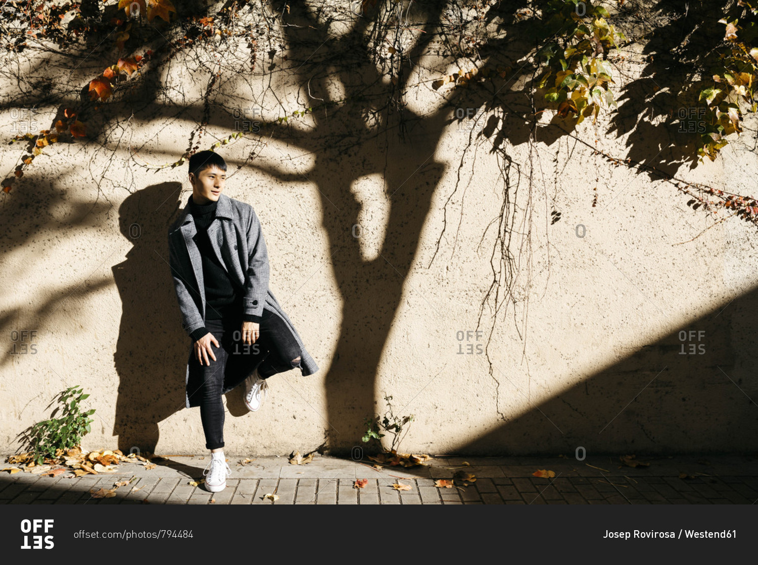Relaxed young man leaning against wall in autumn