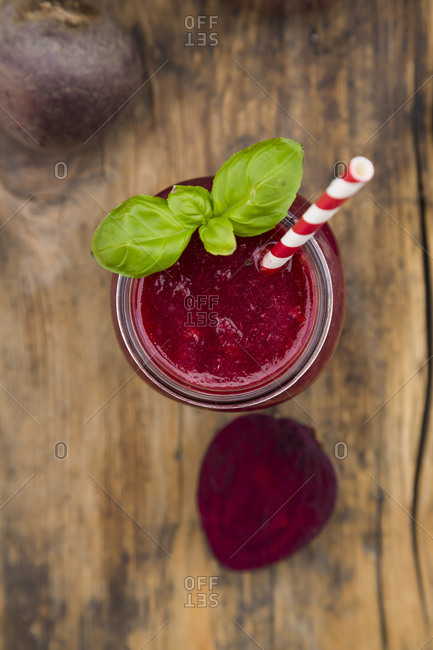 Glass of beet root smoothie garnished with basil leaves