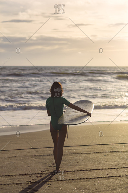 Young woman with surfboard at sunset