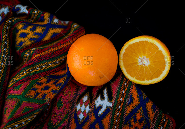 An orange cut in half on a blanket set on a black background