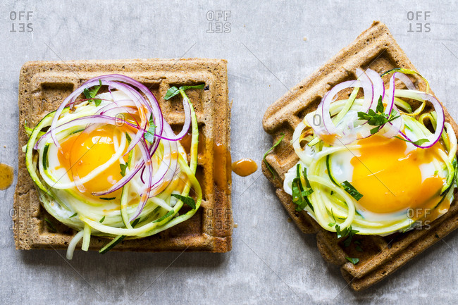 Savory whole grain waffles topped with zucchini zoodles, egg and red onion