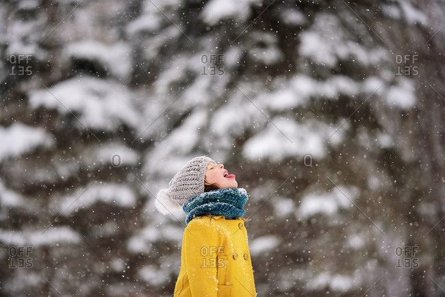 Young girl outside catching snowflakes on her tongue