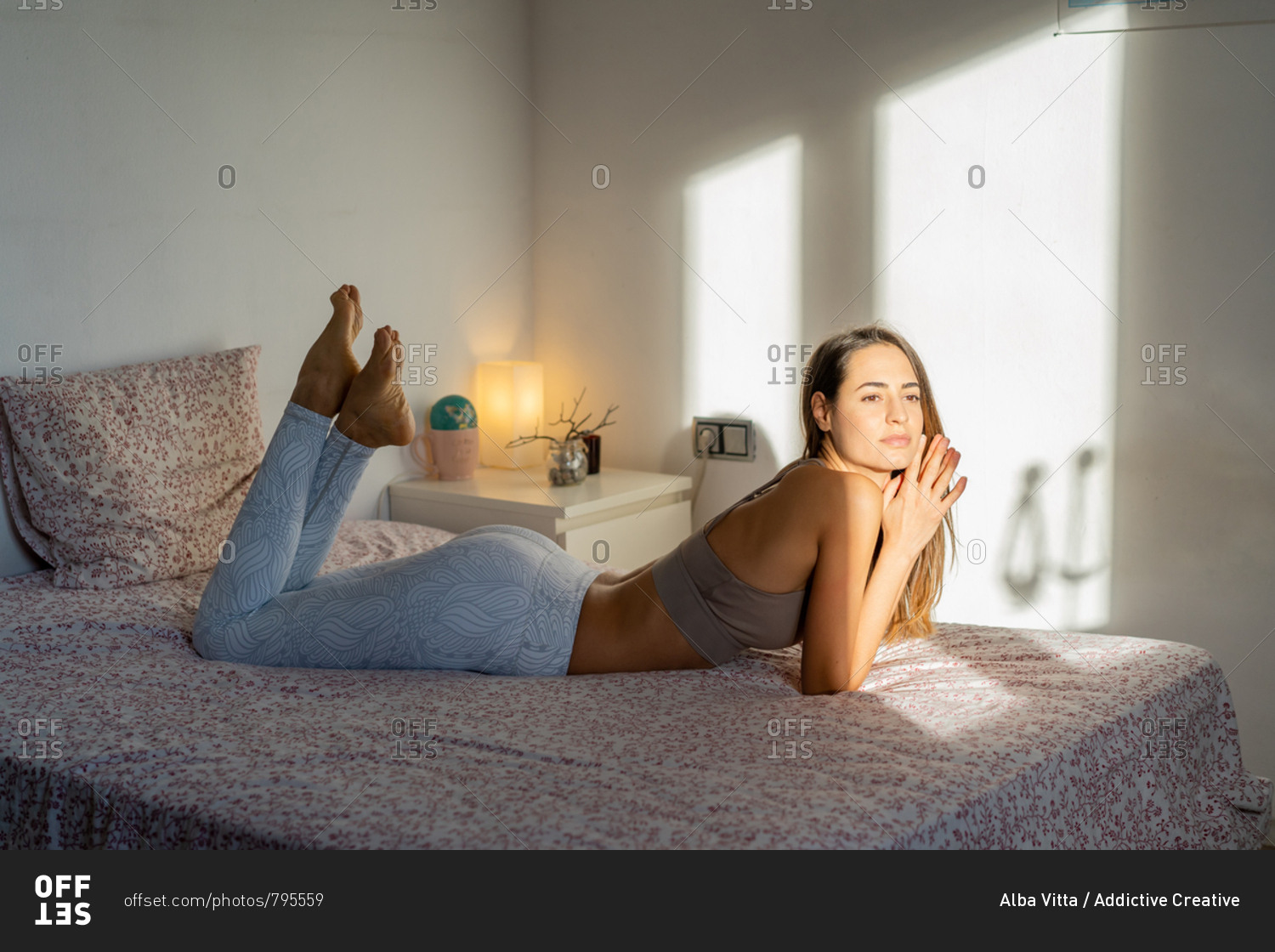 Woman in bra lying on bed stock photo - OFFSET