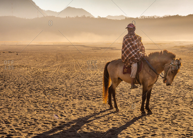 Java Island, Indonesia - August, 14 2015: Anonymous person on horse near volcano