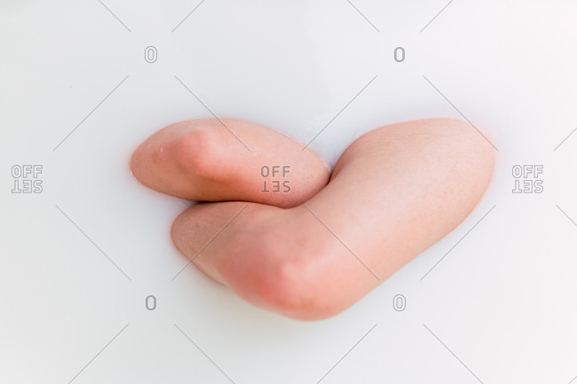 Sensual legs and hand of anonymous female bathing in white water