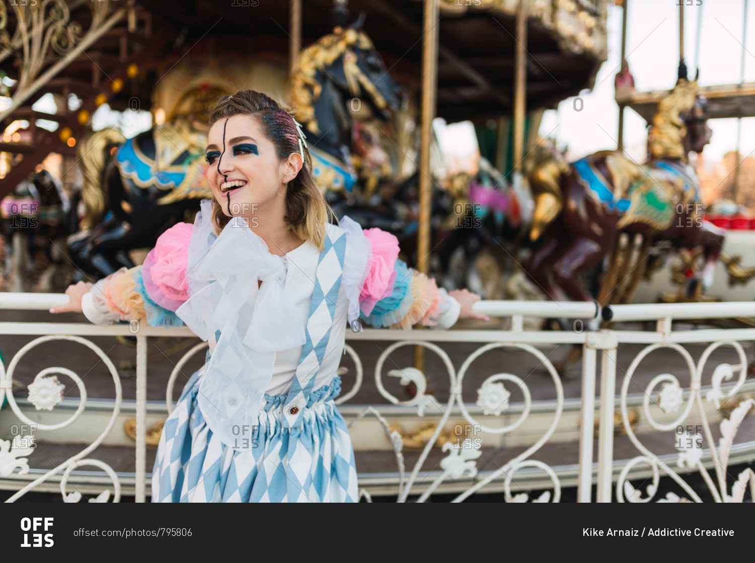 Beautiful young lady with theatrical makeup looking away while standing near carrousel