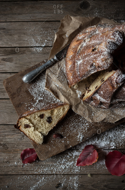 Delicate autumn leaves lying on shabby timber tabletop near plate and parchment paper with yummy fresh Kugelhopf