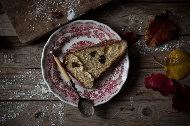 Delicate autumn leaves lying on shabby timber tabletop near plate and parchment paper with yummy fresh Kugelhopf